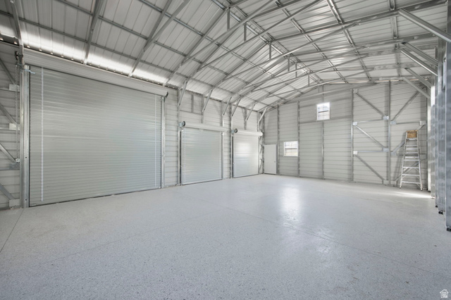 1440 West 100 South Virgin, UT 84779 - Photo 32 of 45 Spacious interior featuring a high arched ceiling with exposed metal truss work, polished concrete flooring, three large roll-up doors, and several windows providing natural light
