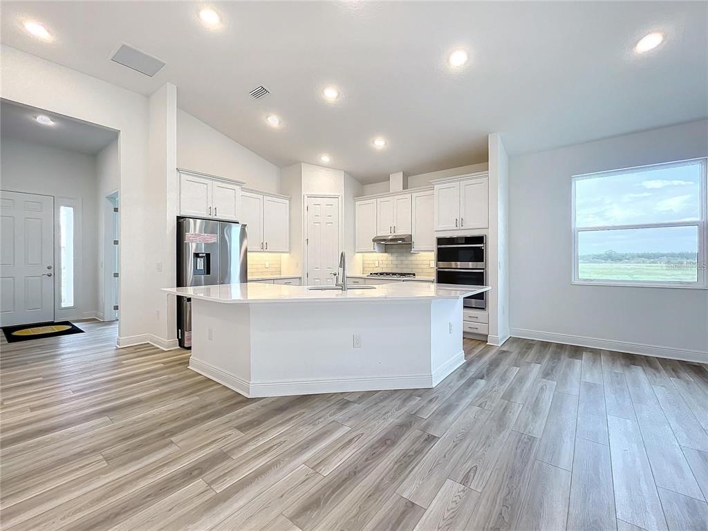 3951 Kennebunk Loop Mount Dora, FL 32757 - Photo 17 of 54 a large kitchen with stainless steel appliances kitchen island a large counter top and a stove top oven