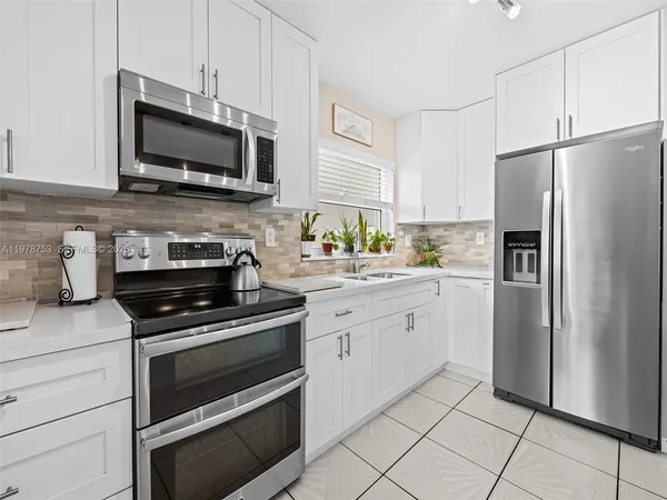 a kitchen with white cabinets stainless steel appliances and a sink