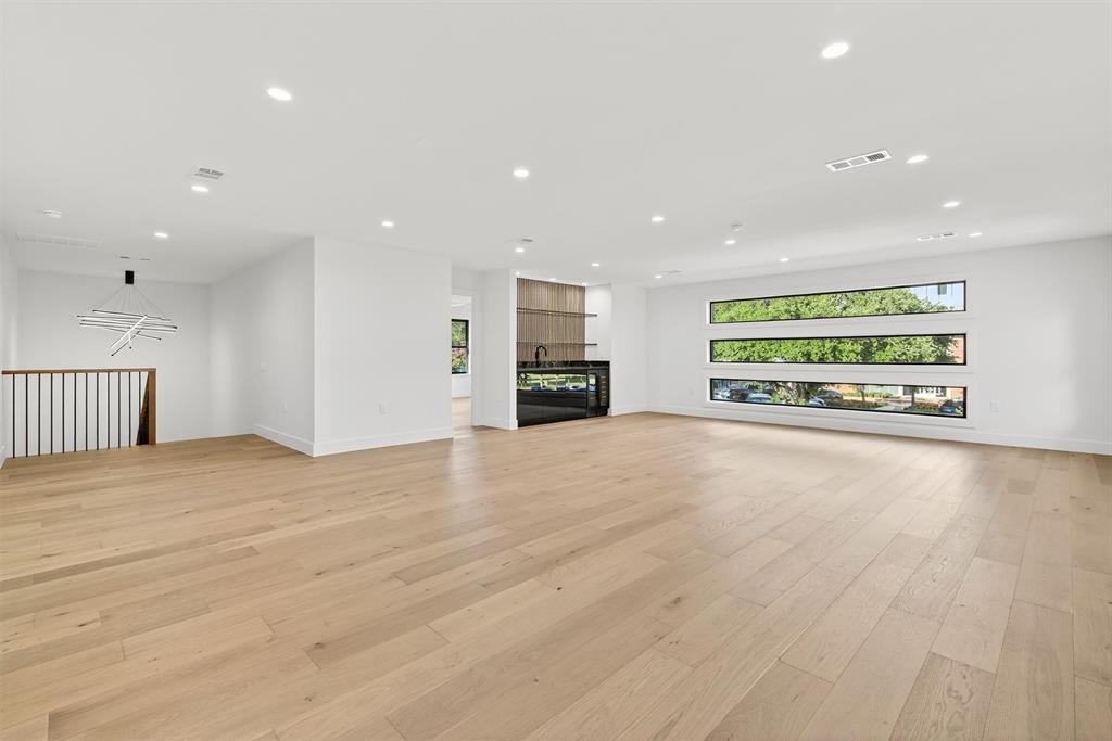 7619 Robin Road Dallas, TX 75209 - Photo 23 of 40 Unfurnished living room with light wood-style flooring, recessed lighting, a glass covered fireplace, and a chandelier