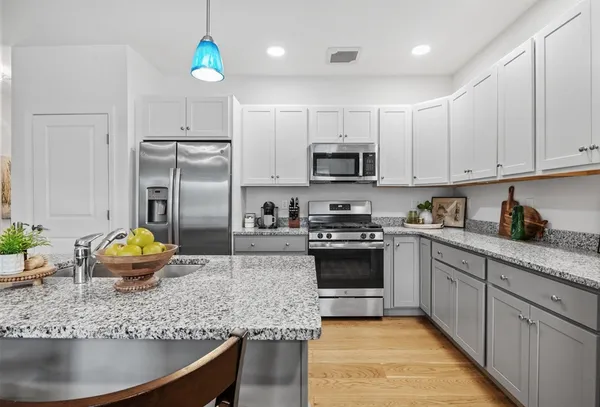 a kitchen with stainless steel appliances granite countertop a sink a stove a refrigerator a center island and cabinets