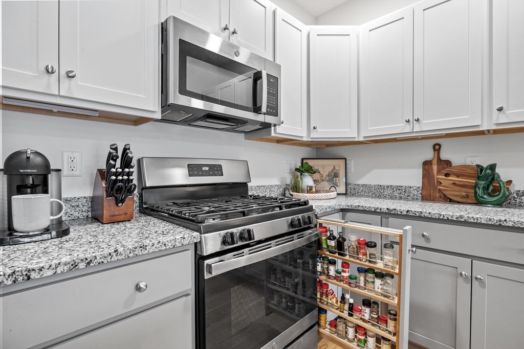 1 Mariner's Way, Unit 204 Plymouth, MA 02360 - Photo 7 of 36 a kitchen with granite countertop white cabinets and stainless steel appliances