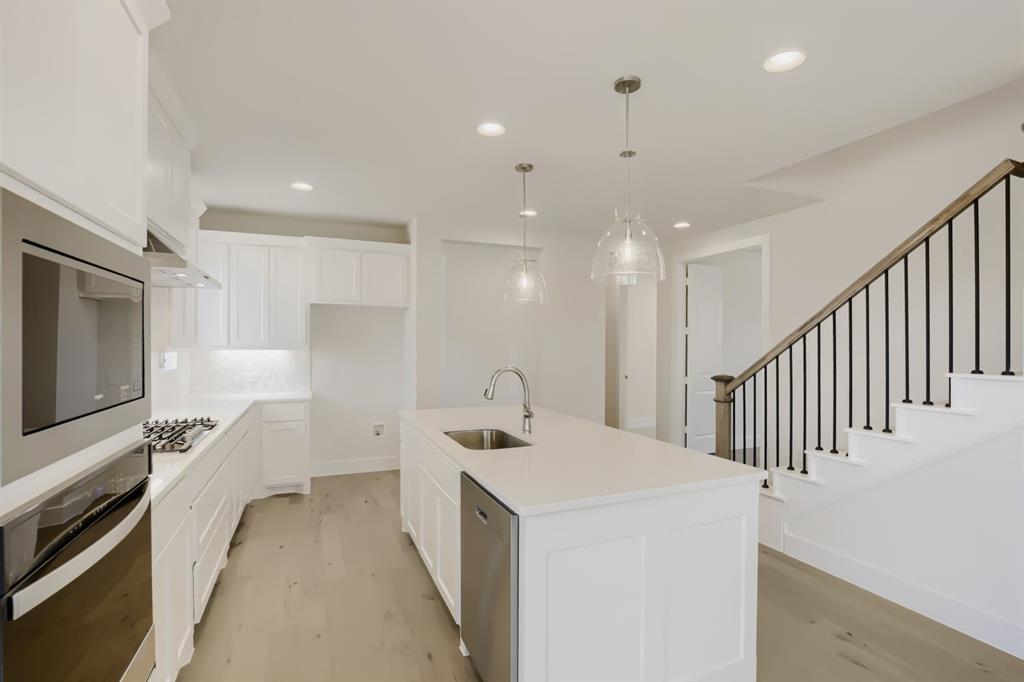 828 Stone Grv Road Lavon, TX 75166 - Photo 5 of 27 Modern kitchen featuring white cabinetry, light-toned countertops, and stainless steel appliances