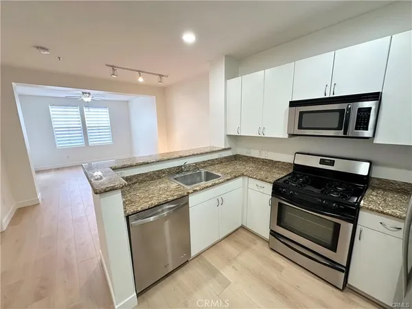 a kitchen with stainless steel appliances granite countertop a refrigerator sink and stove