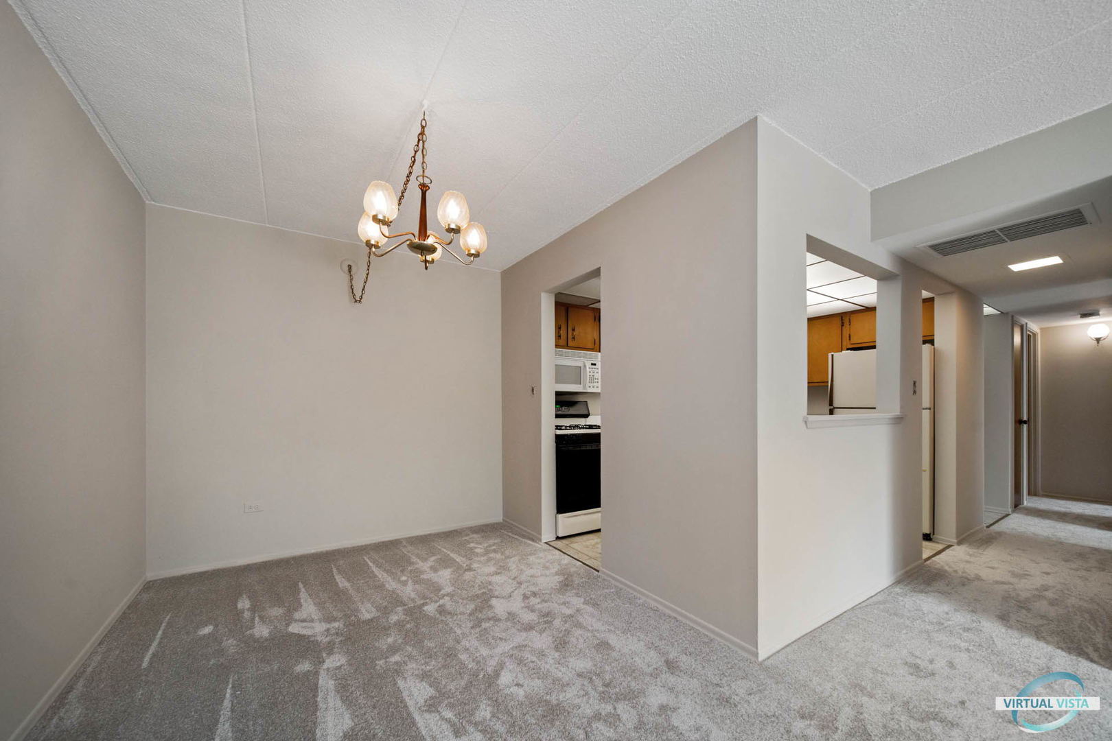100 West Butterfield Road, Unit 210 Elmhurst, IL 60126 - Photo 8 of 27 en empty room with chandelier fan and kitchen view