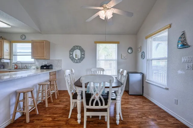 a kitchen with granite countertop a refrigerator a stove a dining table and chairs