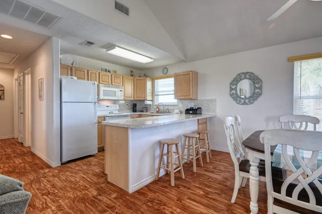 a kitchen with stainless steel appliances granite countertop a stove a sink dishwasher and a refrigerator with wooden floor