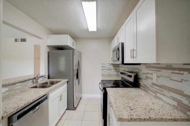 1104 Meadows Circle Boynton Beach, FL 33436 - Photo 12 of 27 a kitchen with a sink stove and cabinets