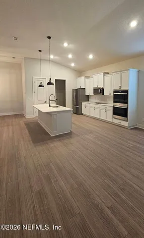 a kitchen with stainless steel appliances a sink a stove a refrigerator and wooden floor