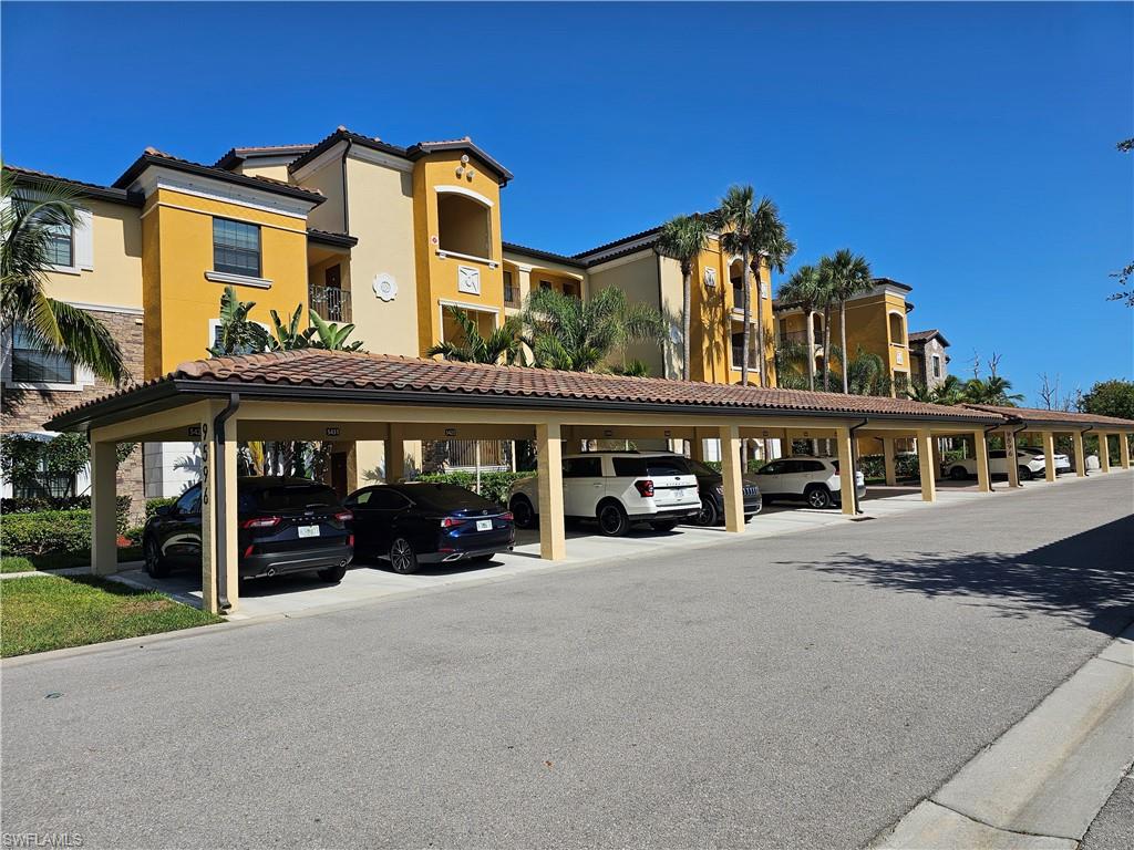 9596 Trevi Court, Unit 5428 Naples, FL 34113 - Photo 20 of 43 a view of a blue house with large windows and a table and chairs under an umbrella