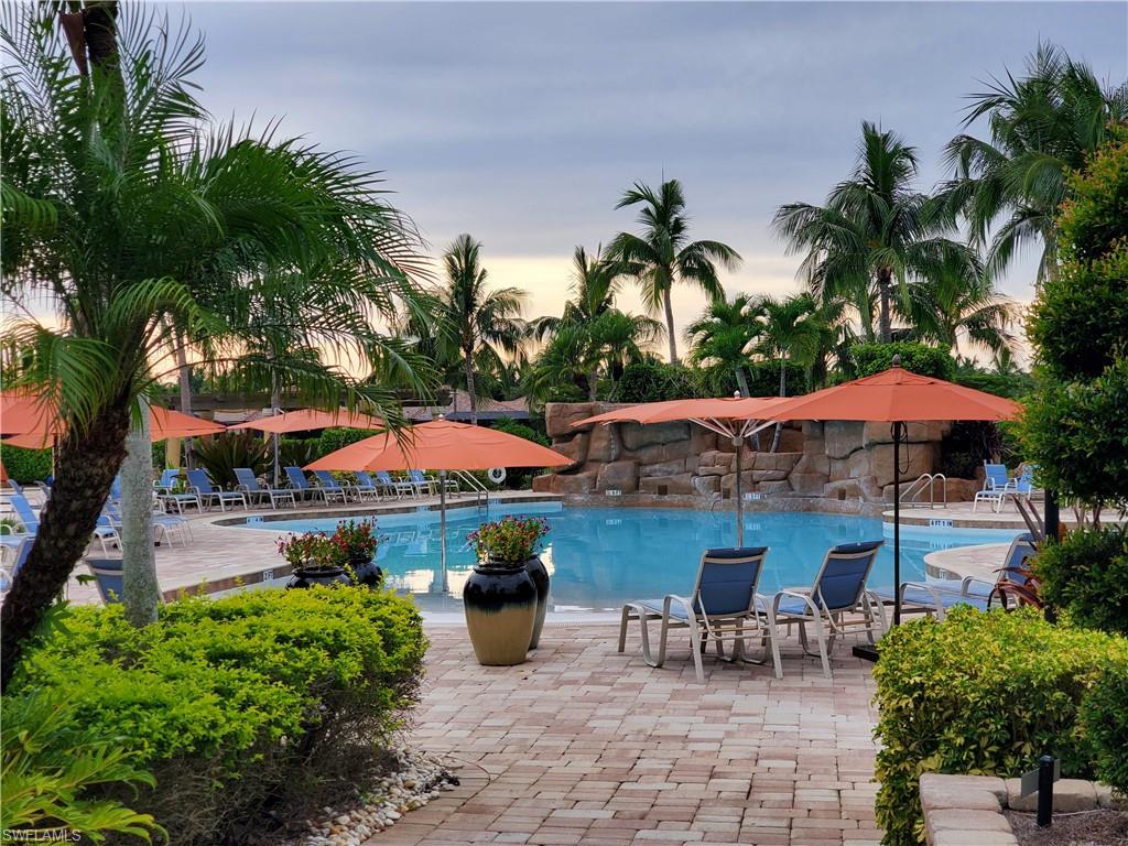 9596 Trevi Court, Unit 5428 Naples, FL 34113 - Photo 25 of 43 a view of a patio with a table and chairs under an umbrella