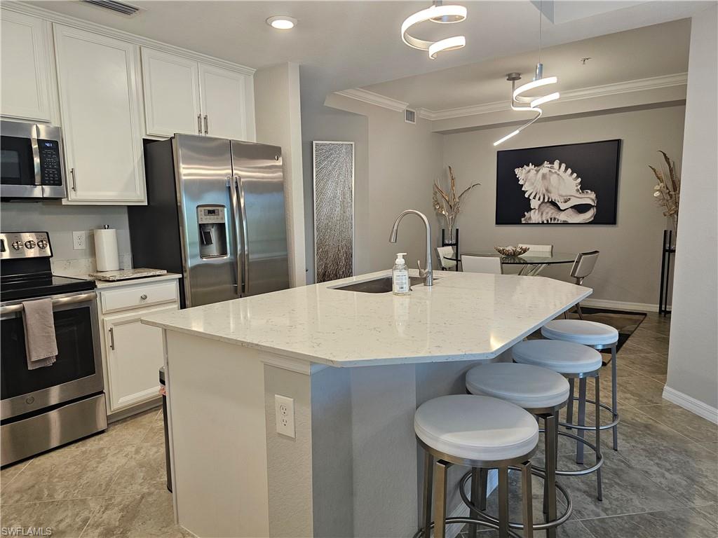 9596 Trevi Court, Unit 5428 Naples, FL 34113 - Photo 5 of 43 a kitchen with stainless steel appliances a table and chairs