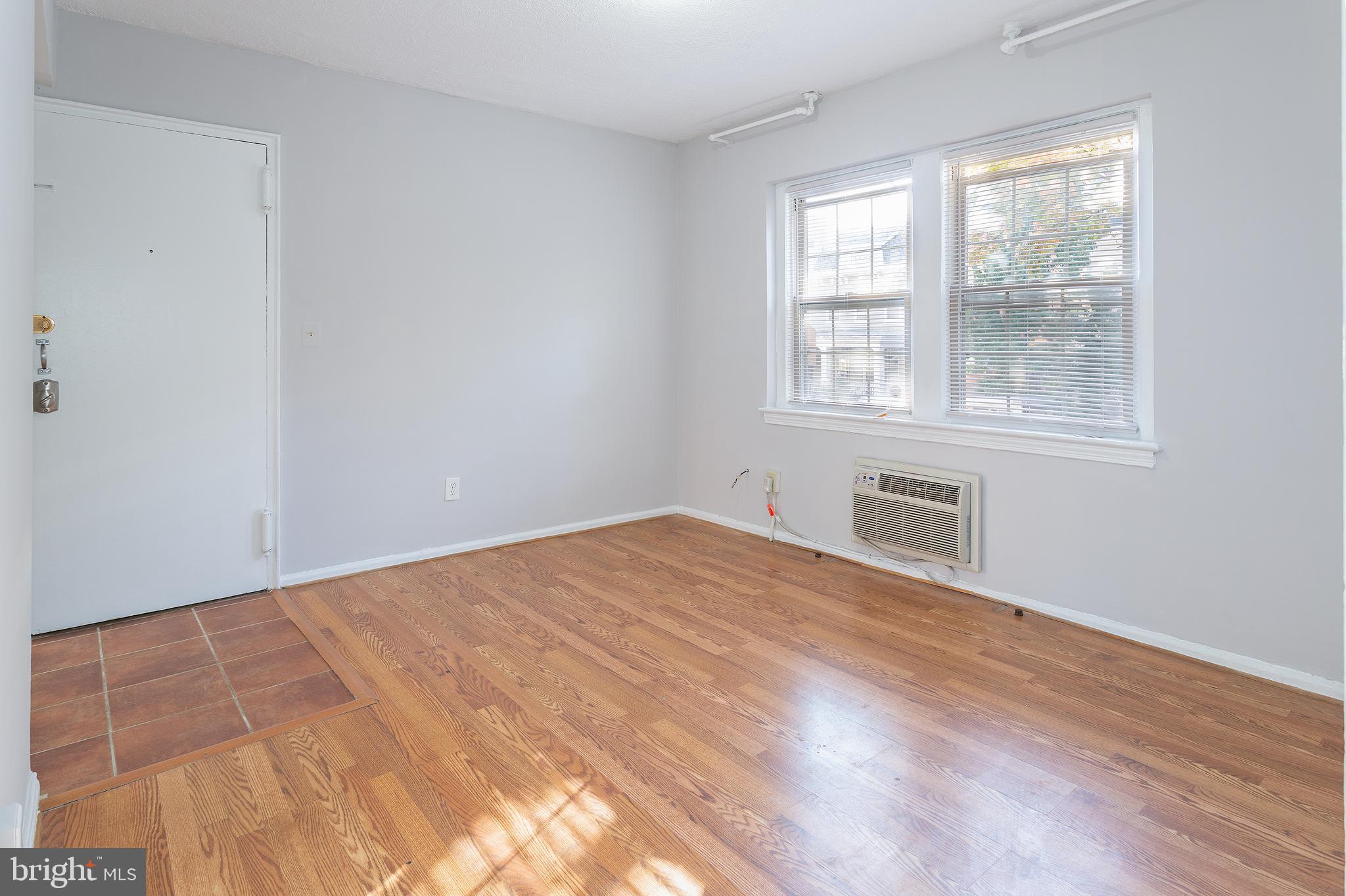 2415 Ontario Road Northwest, Unit 101 Washington, DC 20009 - Photo 11 of 22 a view of an empty room with wooden floor and a window