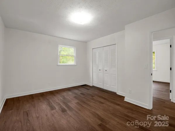 a view of an empty room with wooden floor and windows