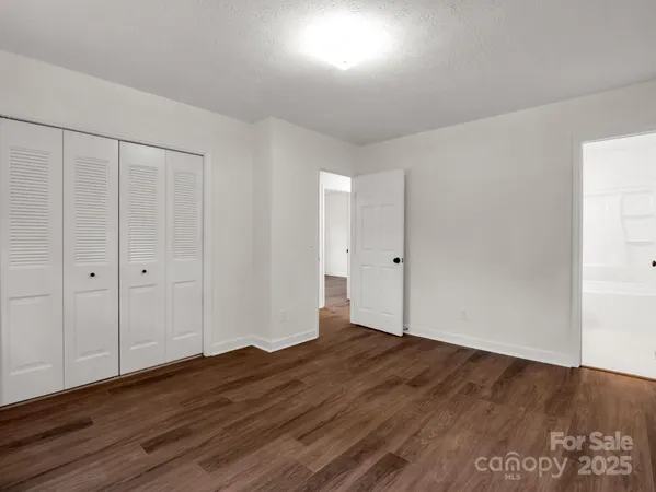 a view of an empty room with wooden floor and fireplace