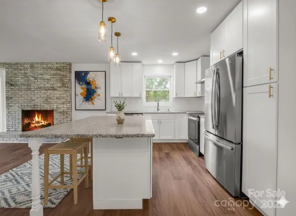 a kitchen with granite countertop stainless steel appliances a refrigerator cabinets a sink and a counter top space