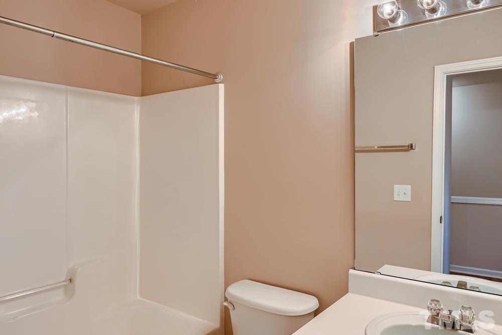 8157 Rhiannon Road Raleigh, NC 27613 - Photo 22 of 27 a white toilet and shower curtain