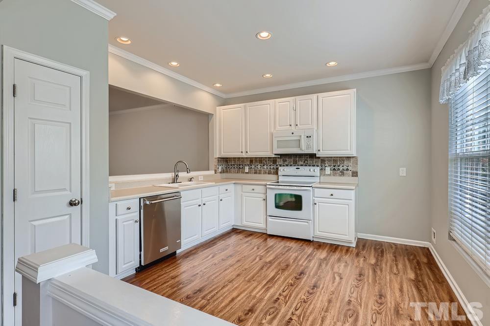 8157 Rhiannon Road Raleigh, NC 27613 - Photo 8 of 27 a kitchen with granite countertop white cabinets and white appliances