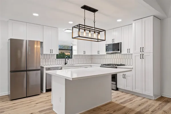 a kitchen with kitchen island stainless steel appliances a sink stove refrigerator and cabinets