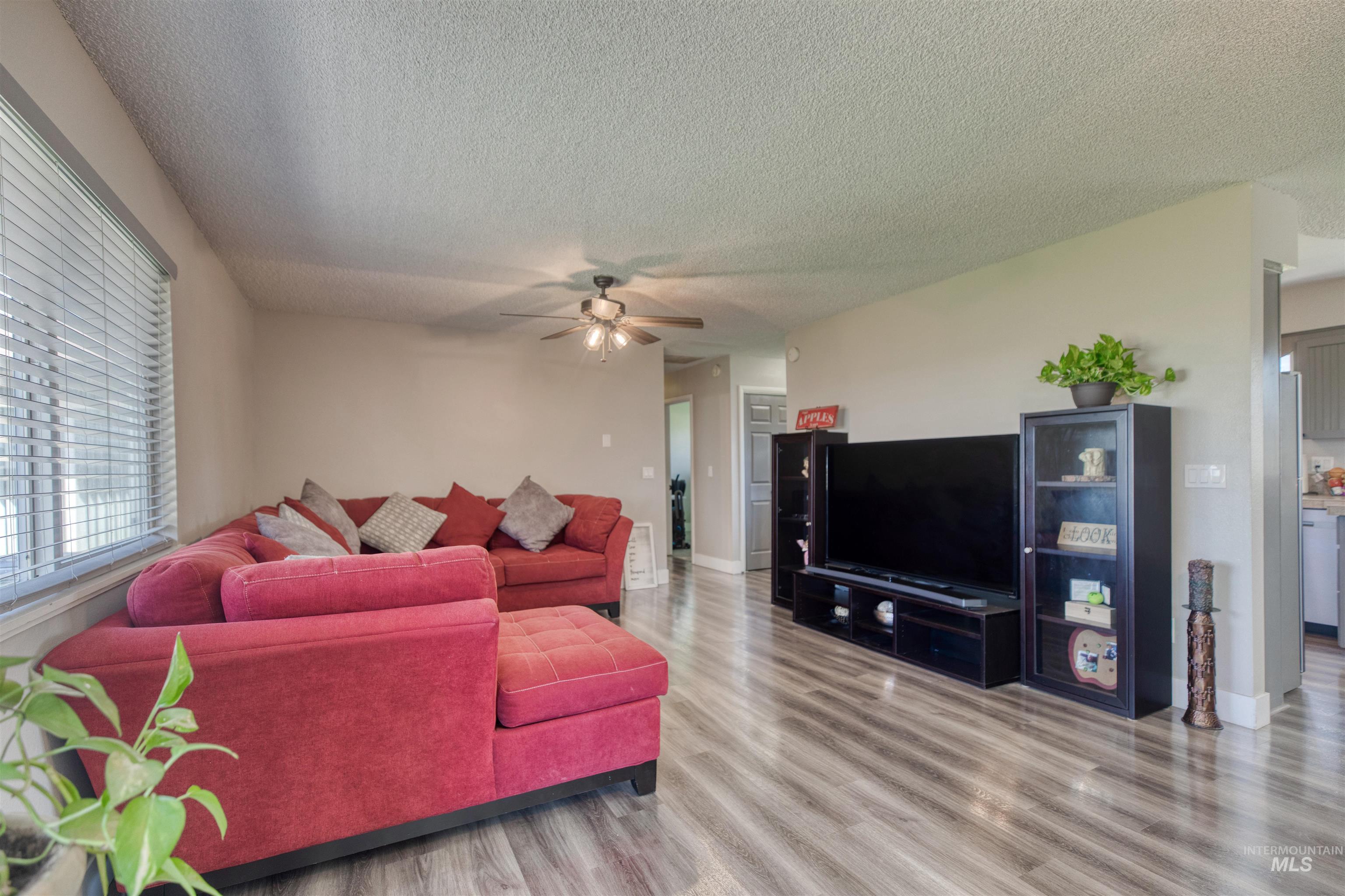 20803 Friends Road Greenleaf, ID 83626 - Photo 10 of 39 Spacious living area featuring wood-finish flooring, a ceiling fan, and window blinds