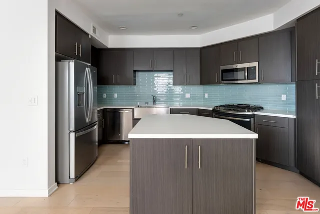 a kitchen with kitchen island stainless steel appliances a sink stove and refrigerator