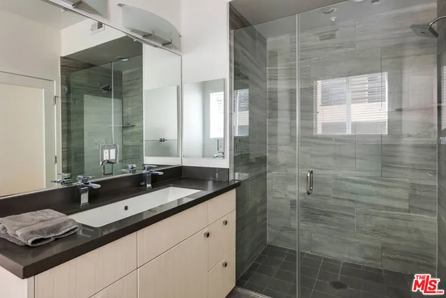 a bathroom with a granite countertop sink a mirror and a shower