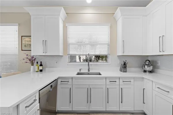 a kitchen with white cabinets and a window