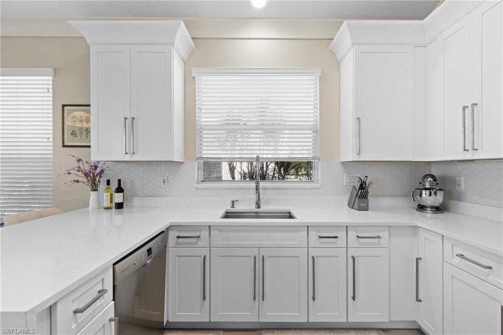 1869 Pondside Lane Naples, FL 34109 - Photo 12 of 34 Kitchen with dishwasher, a peninsula, white cabinetry, and light stone countertops