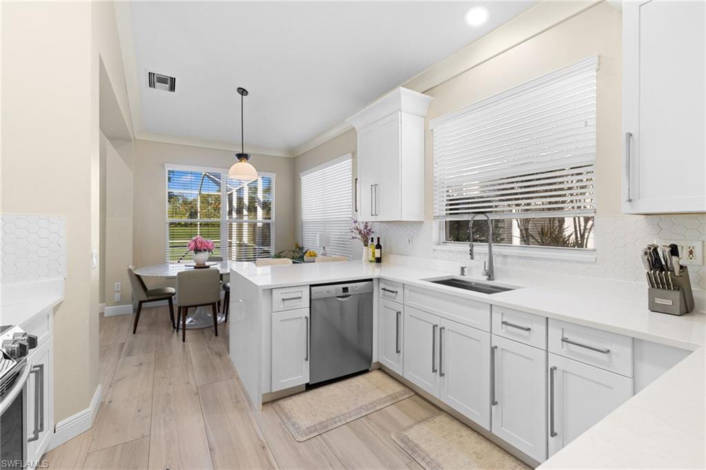 1869 Pondside Lane Naples, FL 34109 - Photo 10 of 34 Kitchen with backsplash, appliances with stainless steel finishes, light stone counters, white cabinets, and decorative light fixtures