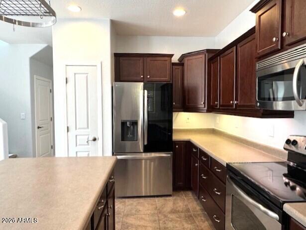 3827 East Trigger Way Gilbert, AZ 85297 - Photo 10 of 41 a kitchen with stainless steel appliances granite countertop a refrigerator a stove and a sink with wooden cabinets