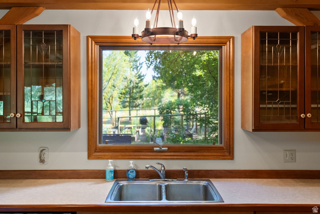 435 Canyon Road Millville, UT 84326 - Photo 17 of 113 Kitchen window with wood trim, dual-basin stainless steel sink, and light-colored countertop