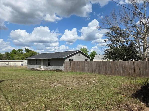 a view of a house with a yard and a large tree