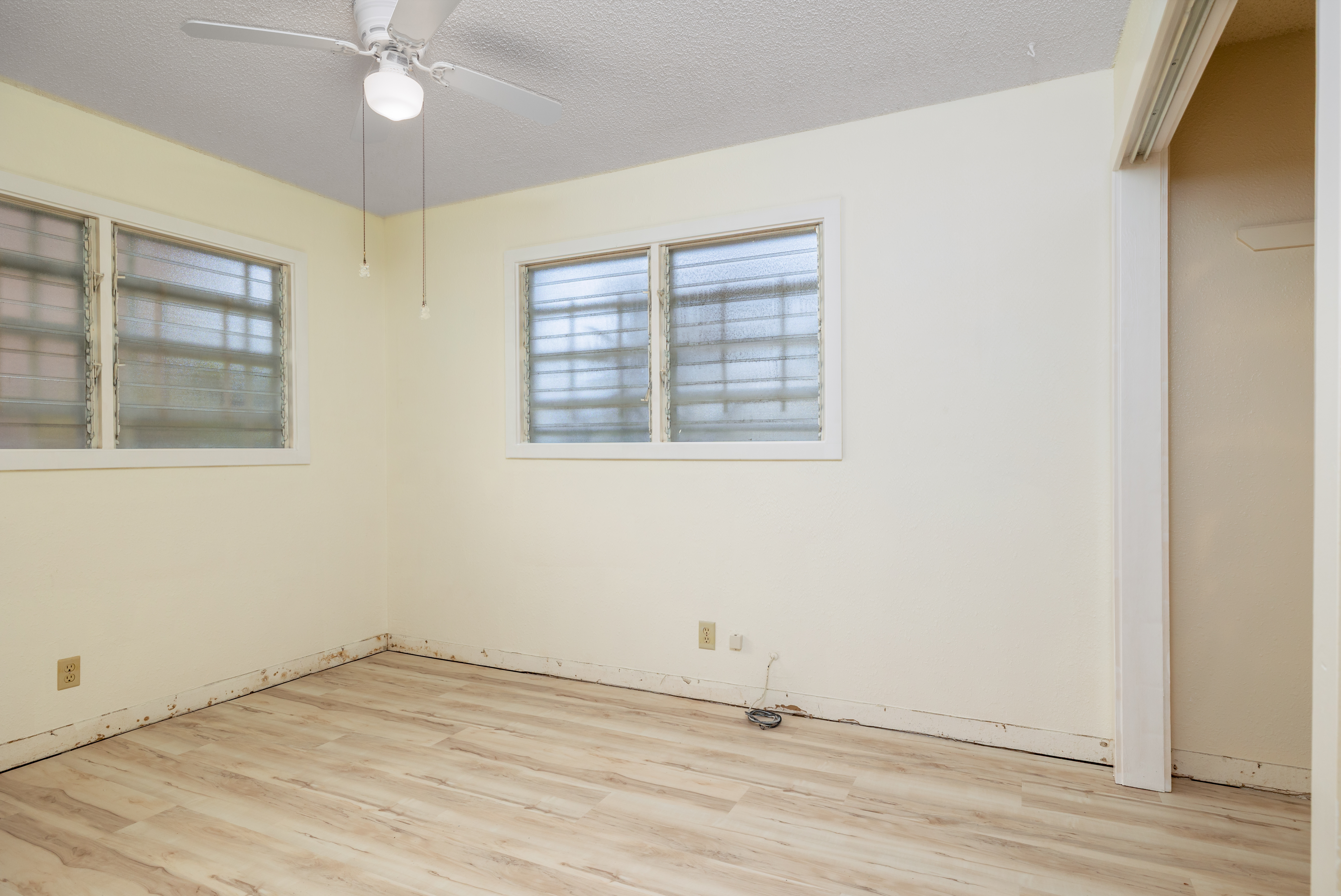 75-185-b Alakai Street, Unit B Kailua-Kona, HI 96740 - Photo 5 of 27 an empty room with wooden floor fan and windows