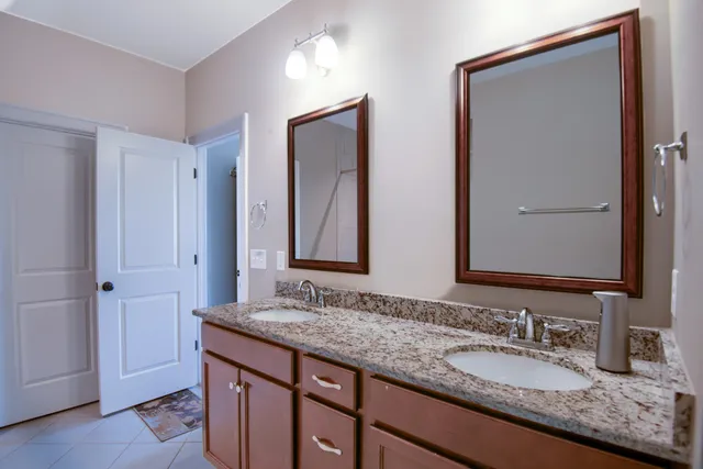 a bathroom with a granite countertop double vanity sink and a mirror