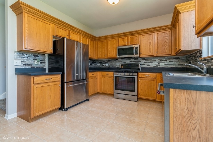 1504 Kempton Street Joliet, IL 60431 - Photo 4 of 15 a kitchen with stainless steel appliances granite countertop a stove refrigerator sink and microwave