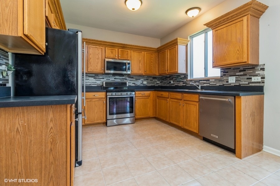 1504 Kempton Street Joliet, IL 60431 - Photo 5 of 15 a kitchen with stainless steel appliances granite countertop a stove a sink and a refrigerator