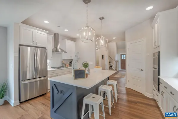a kitchen with stainless steel appliances granite countertop a refrigerator a sink dishwasher a stove and a dining table with wooden floor