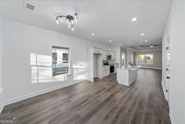 a view of a kitchen and an empty room with wooden floor