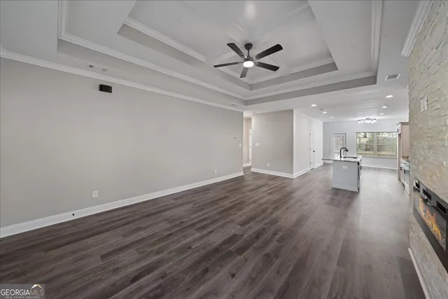 a view of a livingroom with wooden floor a ceiling fan and windows