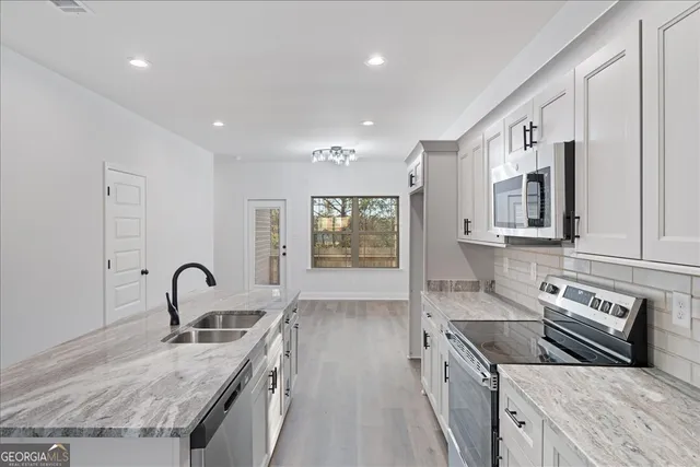 a kitchen with stainless steel appliances granite countertop a sink stove and cabinets