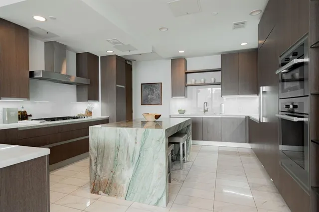 a kitchen with stainless steel appliances kitchen island granite countertop a refrigerator and a stove top oven