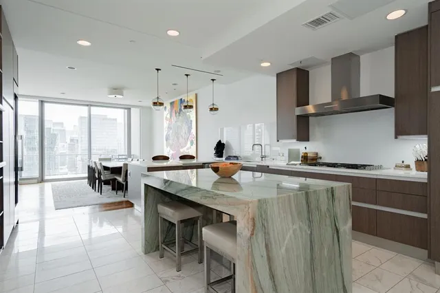 a kitchen with stainless steel appliances granite countertop a stove top oven a sink a dining table and chairs