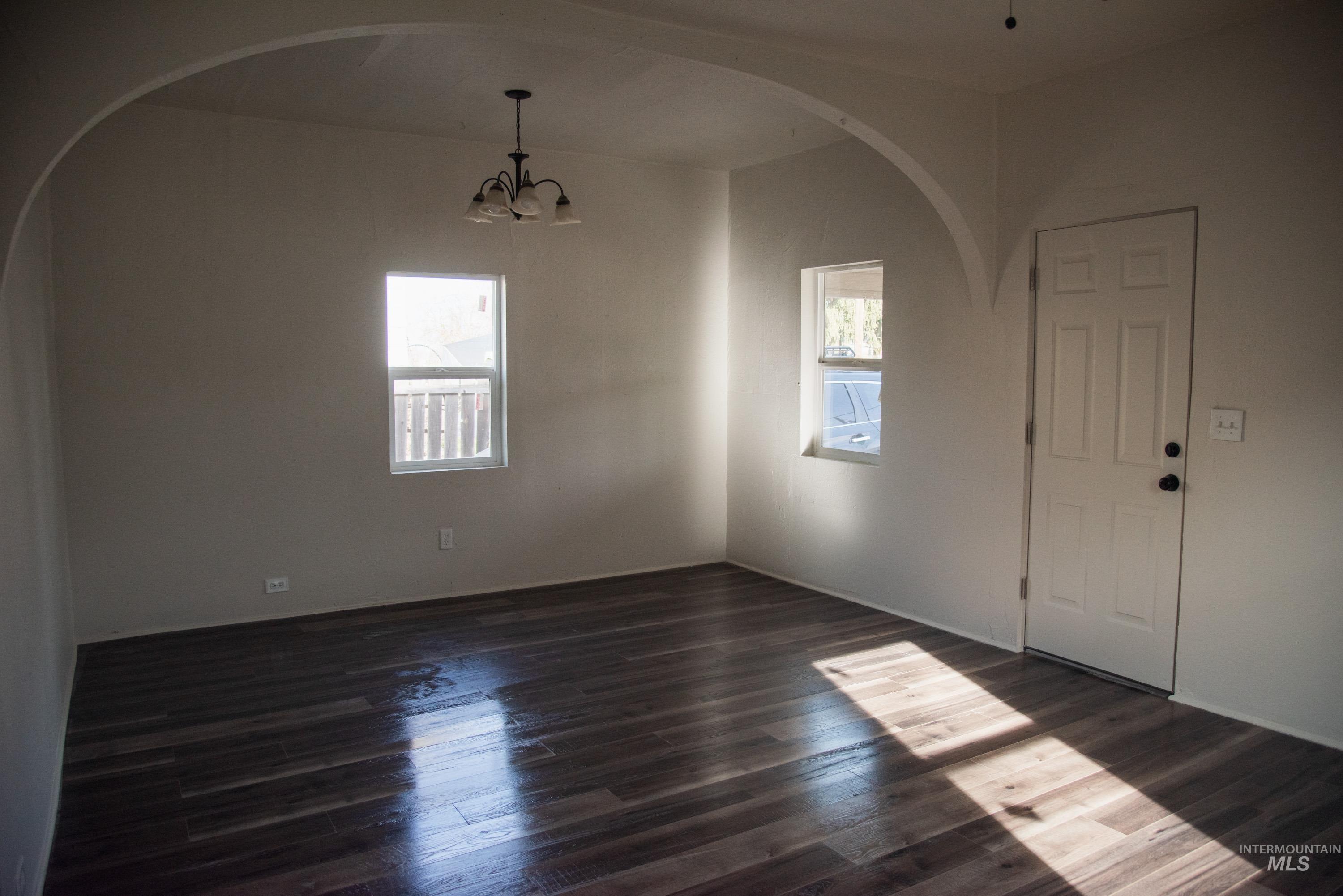 907 North 7th Street Payette, ID 83661 - Photo 13 of 15 Unfurnished dining area featuring healthy amount of natural light, arched walkways, a chandelier, and dark wood finished floors