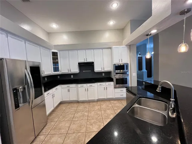 a kitchen with stainless steel appliances granite countertop a sink a stove top oven a refrigerator and a granite counter tops