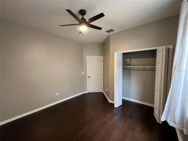 an empty room with wooden floor and a ceiling fan