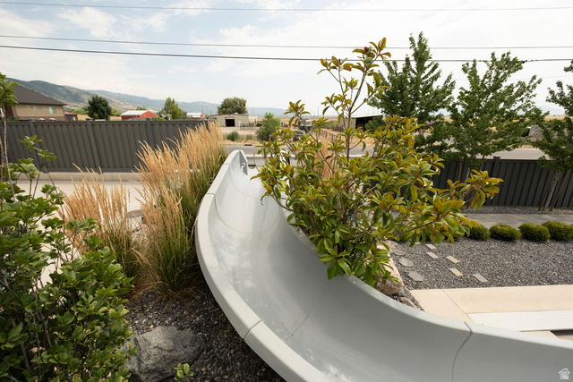 924 Country Lane Farmington, UT 84025 - Photo 64 of 91 Outdoor space featuring a gray slide, decorative gravel, stepping stones, and mature plantings