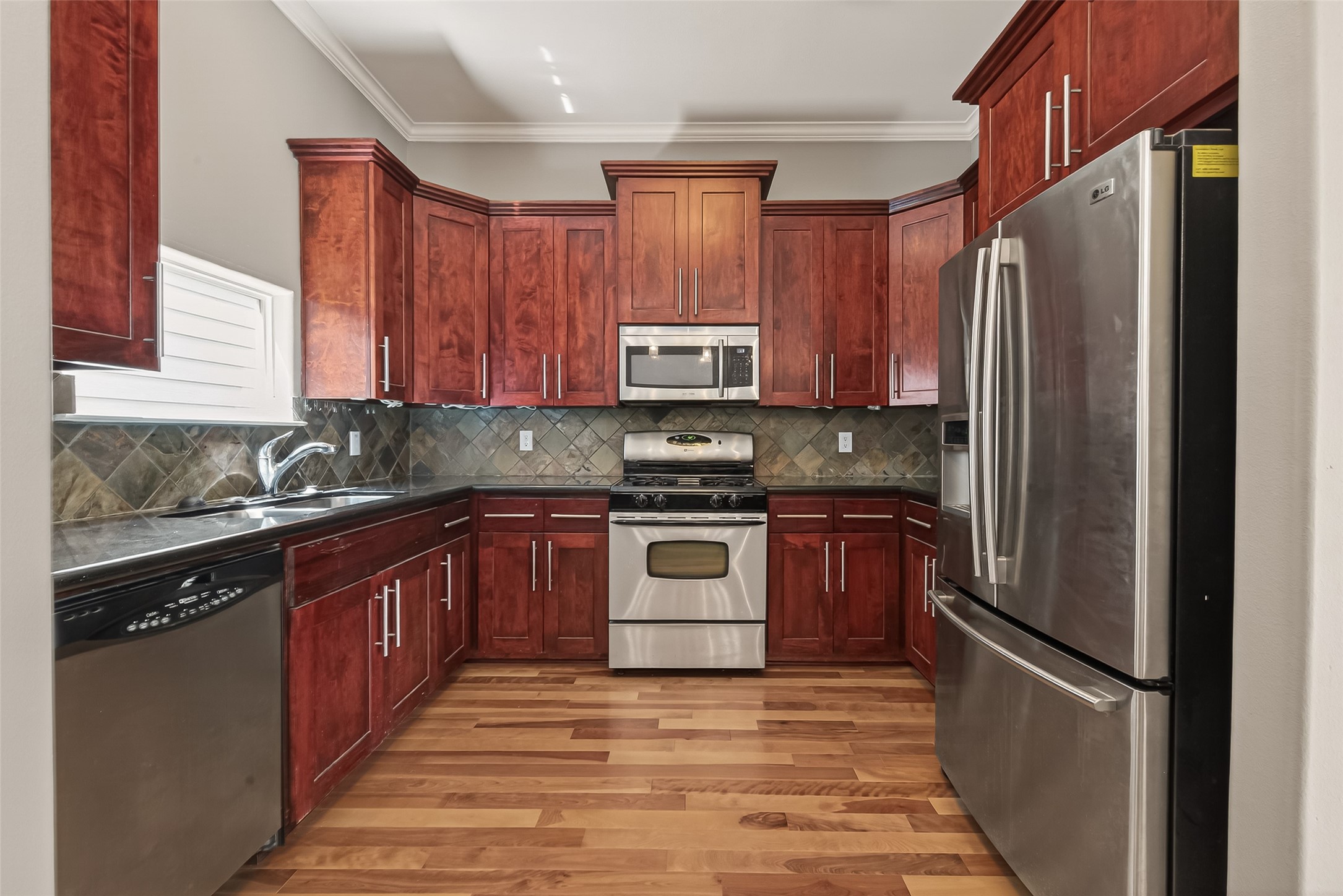 1107 St Charles Street Houston, TX 77003 - Photo 12 of 37 a kitchen with granite countertop wooden cabinets and stainless steel appliances