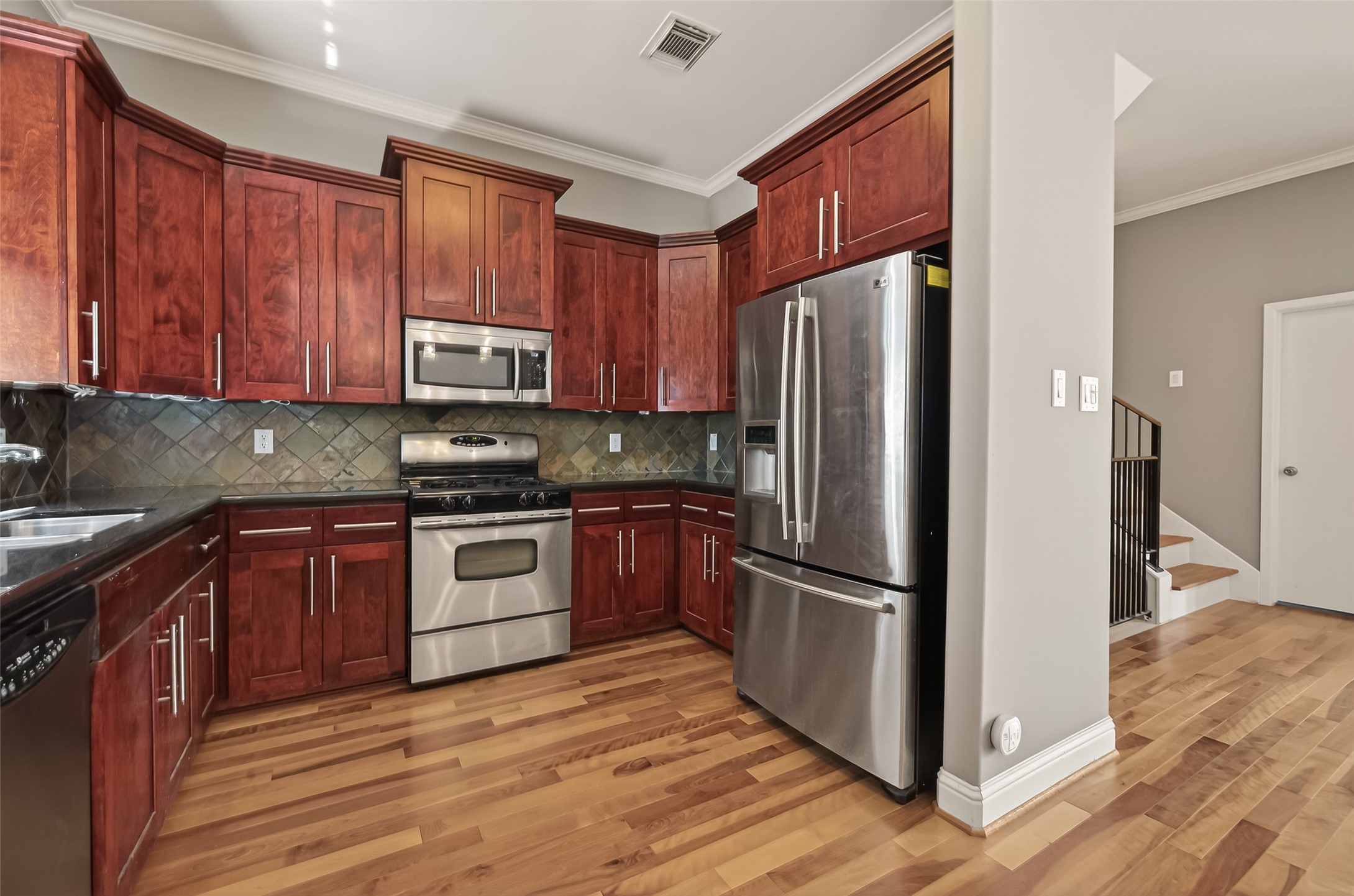 1107 St Charles Street Houston, TX 77003 - Photo 13 of 37 a kitchen with granite countertop wooden floors stainless steel appliances and a sink