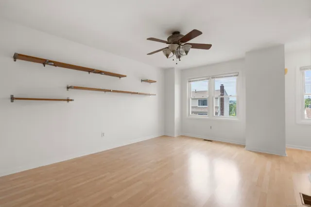 a view of an empty room with a window and wooden floor