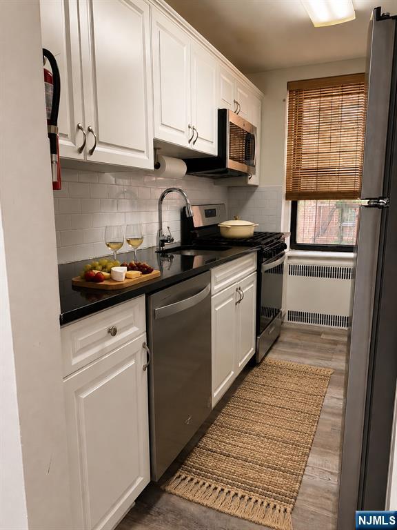 100 Prospect Avenue, Unit 2E Hackensack, NJ 07601 - Photo 10 of 16 a kitchen with stainless steel appliances granite countertop a stove a sink and a microwave